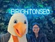 Me standing next to the brightonSEO conference mascot, a seagull called "SEO Gull". There is a neon blue sign saying "BRIGHTONSEO" in the background.