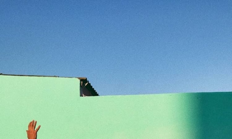 person waving reflecting shadow on teal wall paint