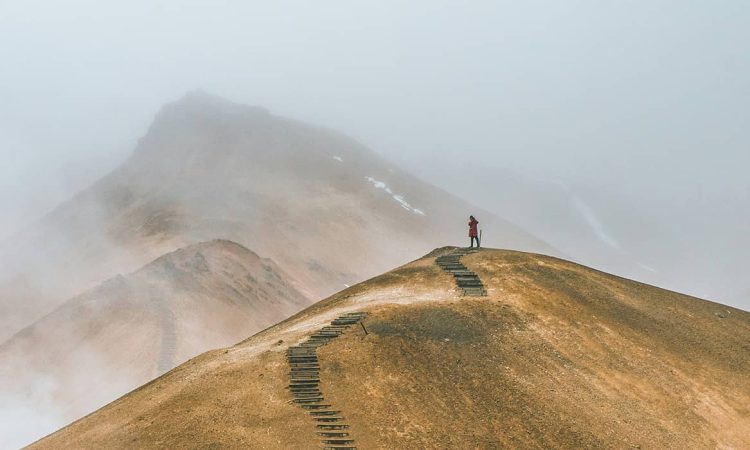 man on top of brown hill