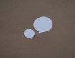 two white speech bubbles sitting on top of a brown surface