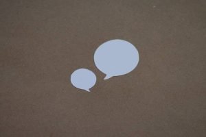 two white speech bubbles sitting on top of a brown surface