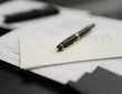 A pen sitting on top of a pile of papers