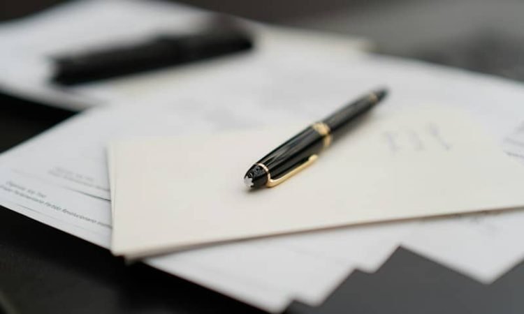 A pen sitting on top of a pile of papers